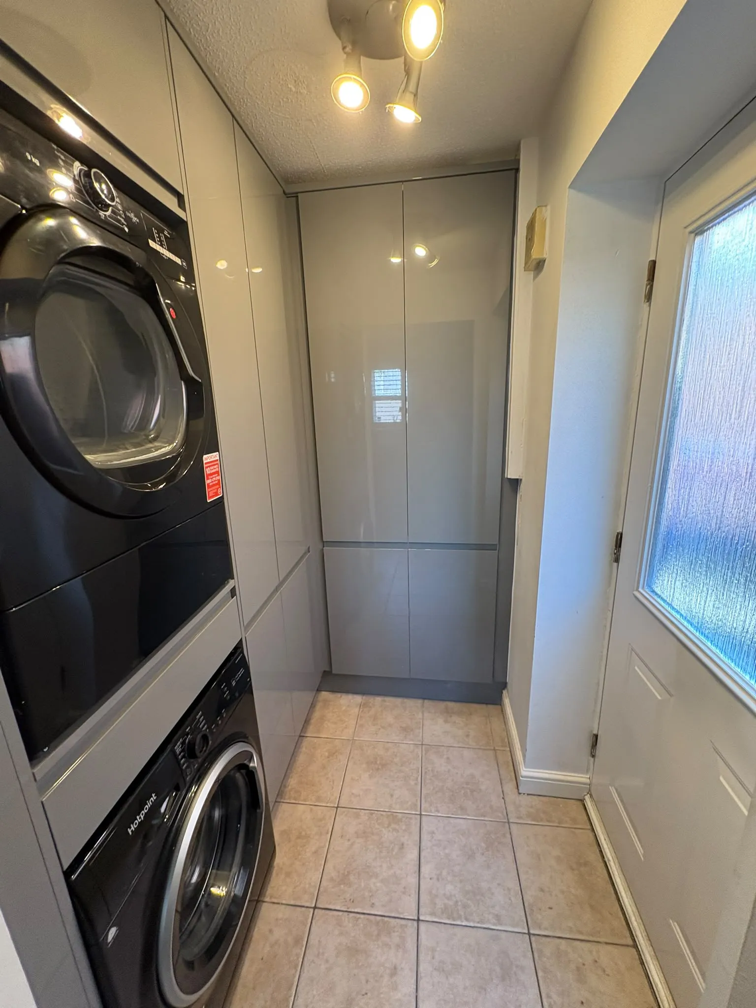 Grey gloss fitted utility room with stacked washer and dryer by LDG Joinery LTD, Bolton