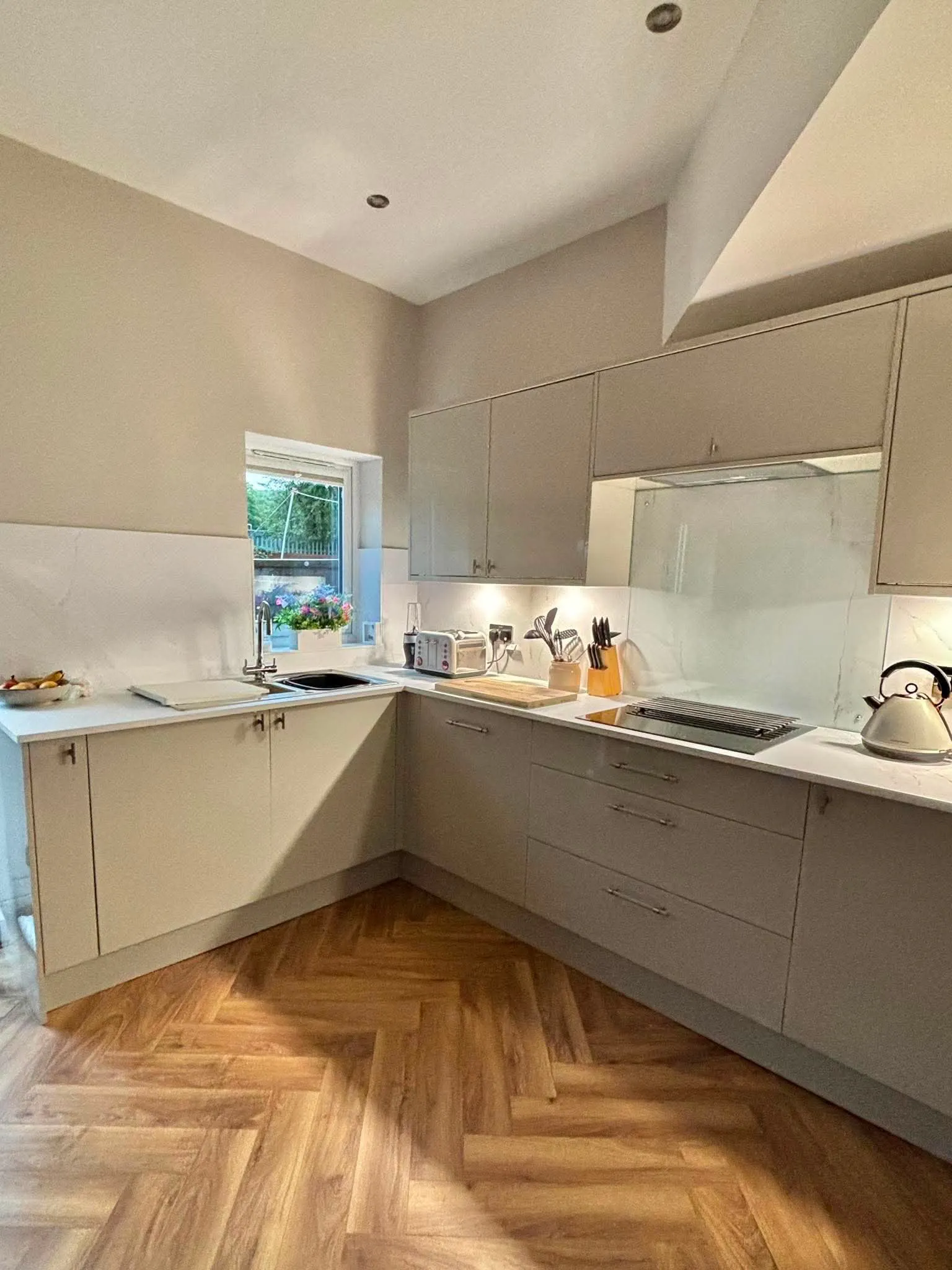 Cream gloss fitted kitchen with herringbone flooring by LDG Joinery LTD, Bolton